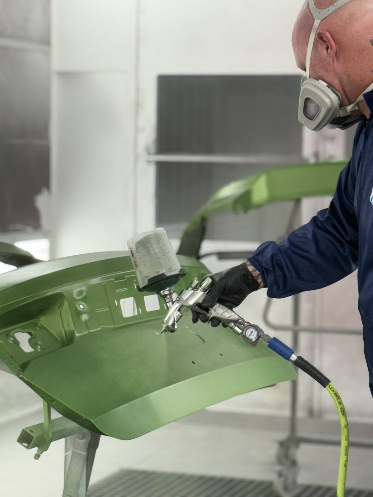 Refinish technician painting a bumper at Renew Collision