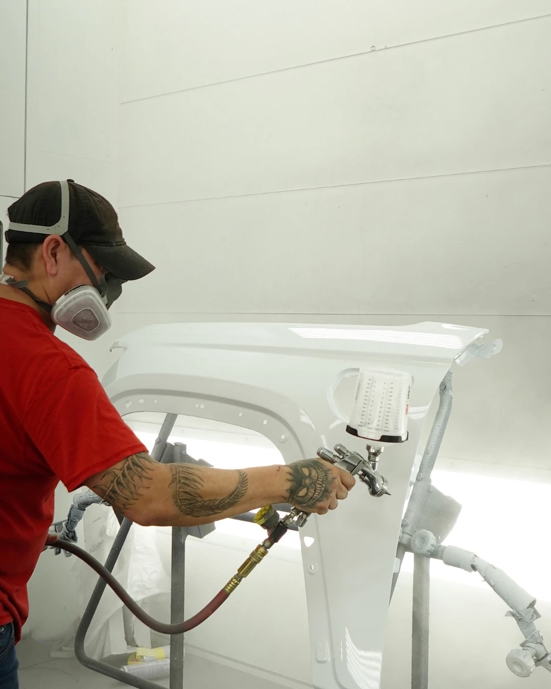 Renew Collision painter refinishing a vehicle in the paint booth